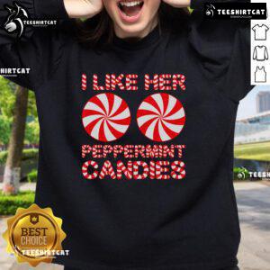 Couple in matching 'I Like Her Peppermint Candies' sweatshirts, celebrating Christmas together in a festive setting.
