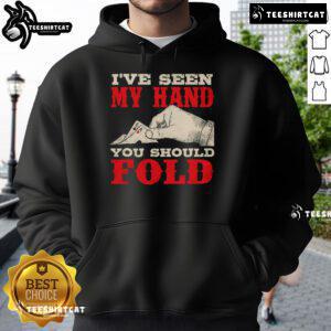 Poker player in a hoodie at the casino, confidently showing hand, suggesting to fold in an intense game.