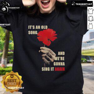 Alt Text: Hadestown Old Song sweatshirt featuring lyrics from 'It's An Old Song And We're Gonna Sing It Again' design.