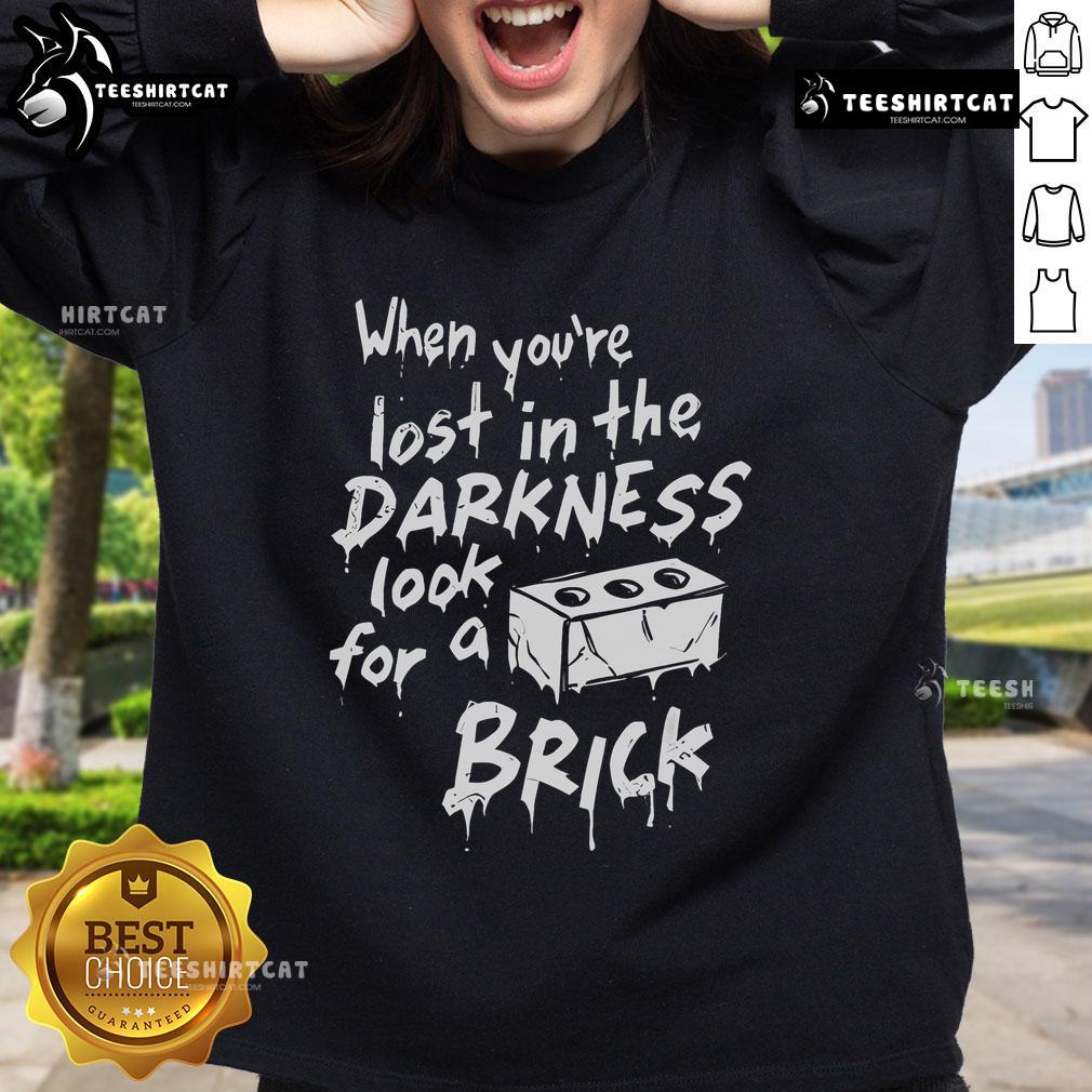 Official 'When You're Lost In The Darkness Look For A Brick' sweatshirt displayed on a hanger, showcasing its unique design.
