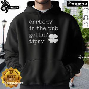 Group of friends wearing St. Patrick's Day hoodies enjoying drinks and celebrations in a lively pub atmosphere.