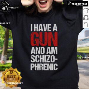 Person wearing a 'I Have A Gun And Am Schizophrenic' sweatshirt, showcasing bold text design and casual style.