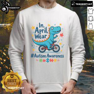 Cute dinosaur in a sweatshirt promoting Autism Awareness for April, showcasing colorful designs and a friendly smile.