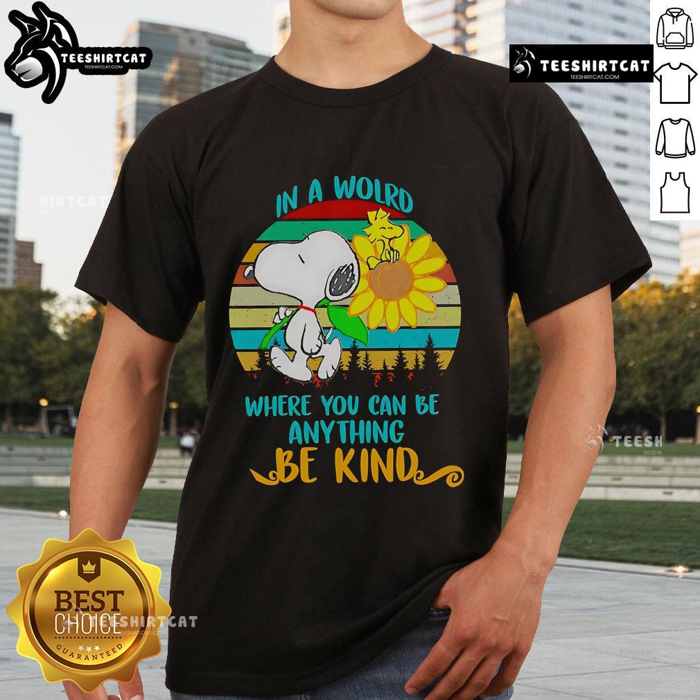 Alt Text: Happy Snoopy sunflower graphic on a retro t-shirt with the quote In a world where you can be anything, be kind.