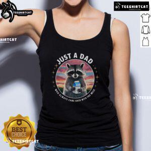 Pretty raccoon wearing a tank top that says 'Just Dad Who Always Came Back With Milk' in a playful outdoor setting.