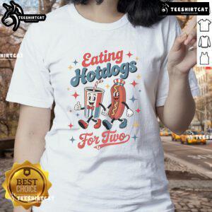 Two ladies enjoying hotdogs at a picnic, wearing the 'Nice Eating Hotdogs' tee, smiling and having a great time outdoors.