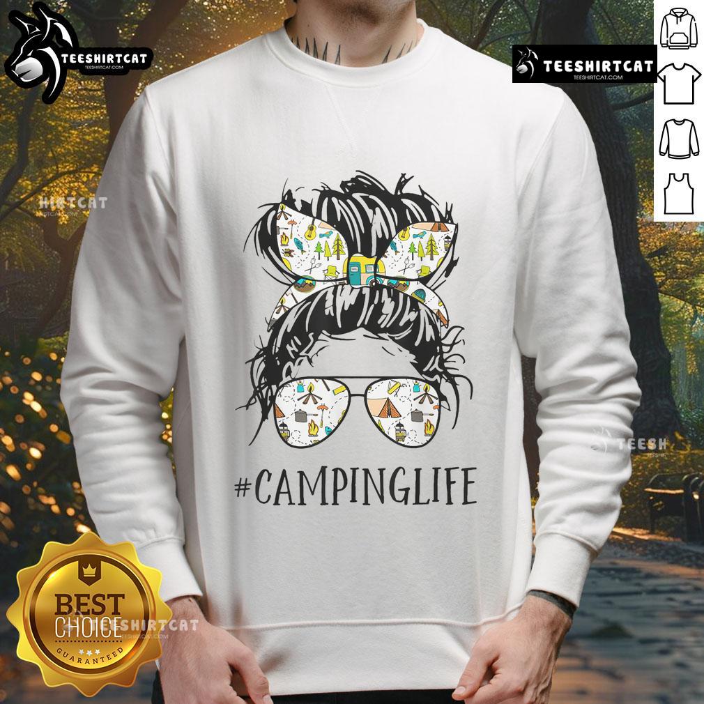 Mom in a messy bun wearing a 'Pretty Camping Life' sweatshirt, enjoying a cozy camping experience in nature.
