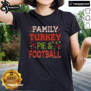 Pretty family enjoying turkey pie while watching football in a cozy living room, showcasing the 'Turkey Pie and Football' tee.