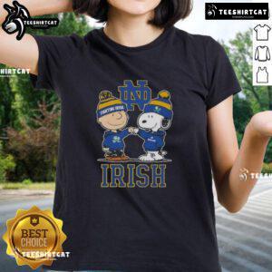 Alt Text: Cute Snoopy and Charlie Brown in Notre Dame Fighting Irish football gear with a skyline, perfect for ladies' tee.