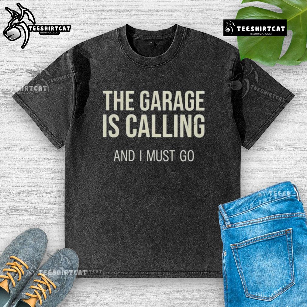 Hot The Garage Is Calling And I Must Go washed t-shirt displayed on a hanger, perfect for car enthusiasts and casual wear.