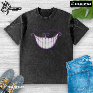 Cheshire Cat smile on a washed t-shirt with 'We Are All Mad Here' text, perfect for whimsical fashion lovers.