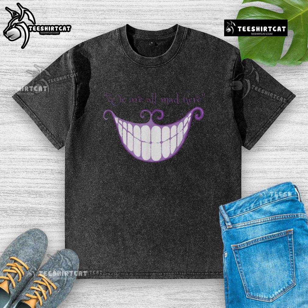Cheshire Cat smile on a washed t-shirt with 'We Are All Mad Here' text, perfect for whimsical fashion lovers.