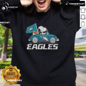 Philadelphia Eagles flag sweatshirt featuring Snoopy and Woodstock driving a car, perfect for fans and cozy wear.