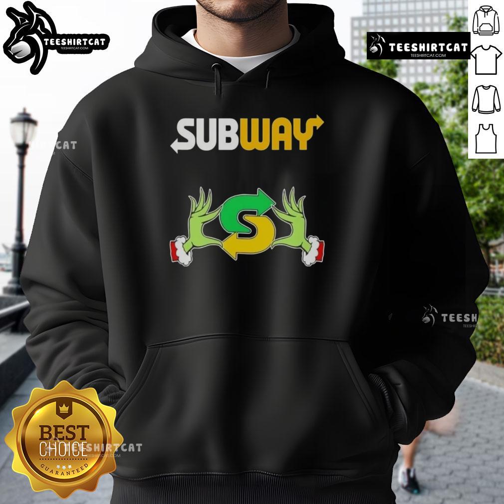 Top Grinch hands holding a Merry Christmas Subway hoodie, perfect for festive holiday wear and celebrating the season.
