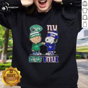 Pretty Charlie Brown fist bump with Snoopy, wearing a New York City Jets vs Giants sweatshirt, showcasing sports spirit.