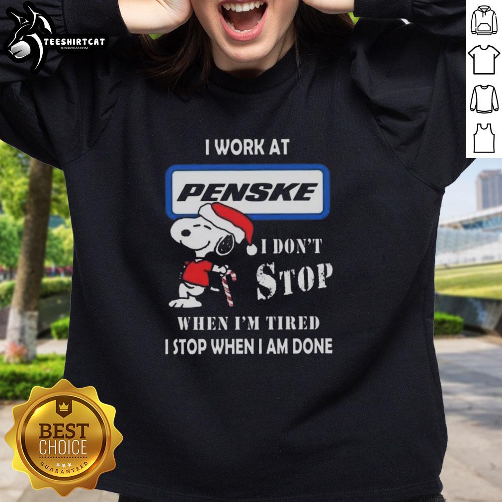 Cozy Christmas sweatshirt featuring Snoopy with 'I Work At Penske Corporation' and motivational quote for festive style.