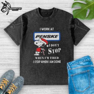Alt Text: Snoopy graphic t-shirt featuring 'I Work at Penske Corporation' and motivational quote for Christmas.