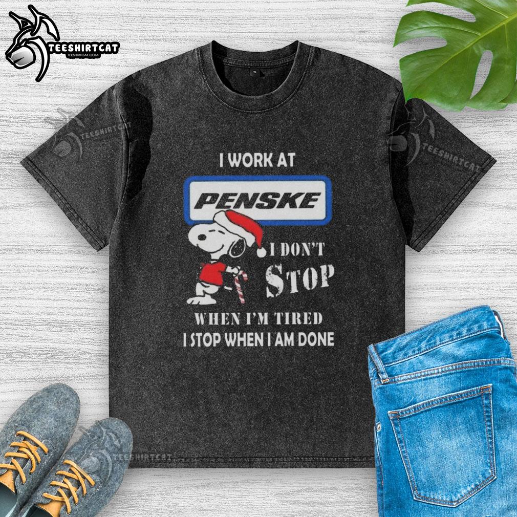 Alt Text: Snoopy graphic t-shirt featuring 'I Work at Penske Corporation' and motivational quote for Christmas.