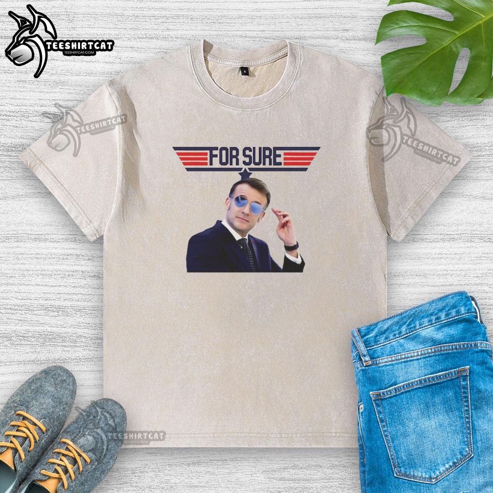 Emmanuel Macron in a washed t-shirt featuring the Top Gun logo, showcasing a casual style and political flair.