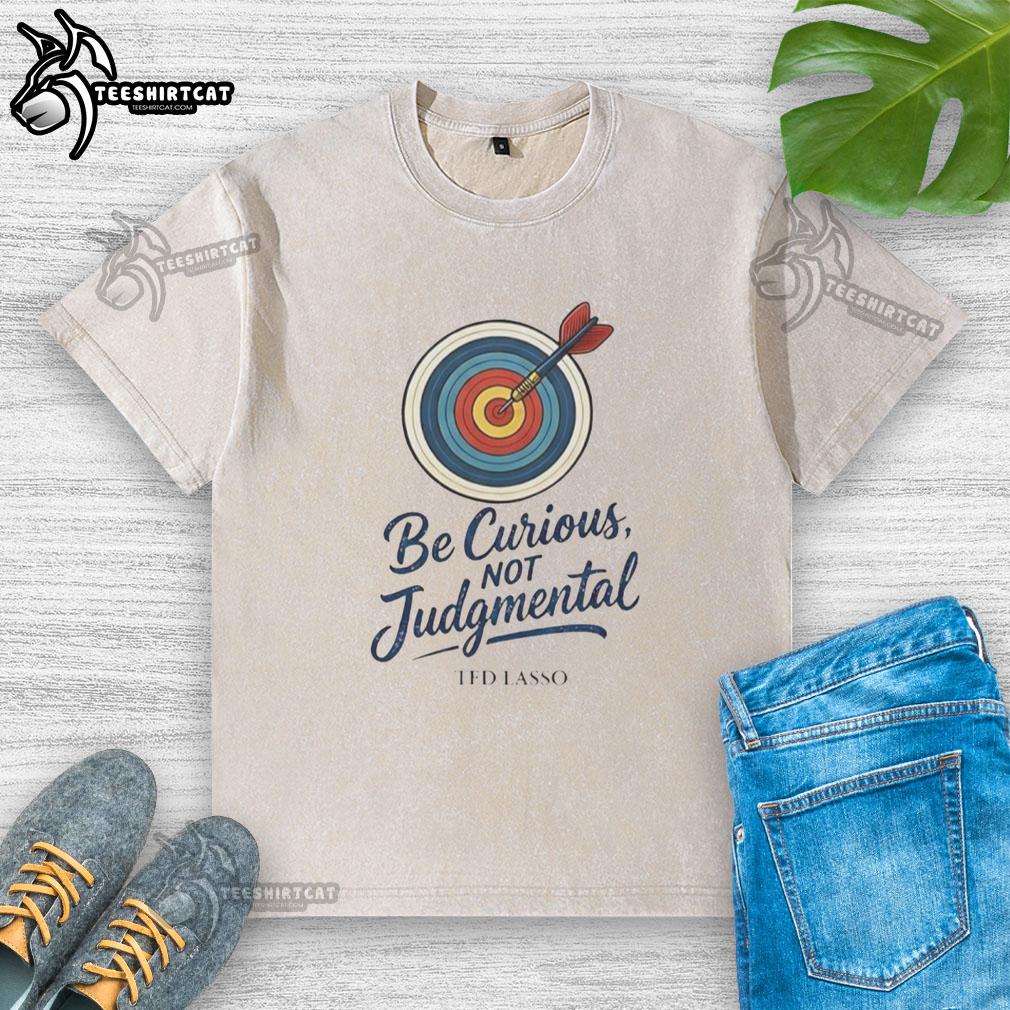 Nice Ted Lasso Be Curious Not Judgmental washed t-shirt displayed on a hanger, showcasing a casual and inspirational design.